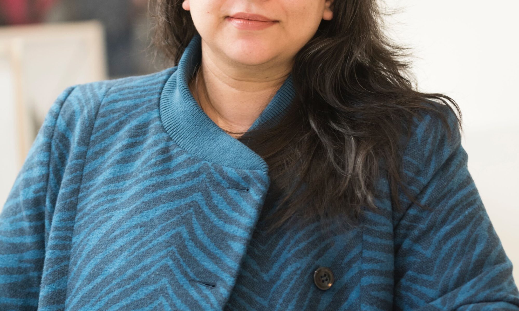 Charming image of woman with lang dark hair doming down over her stylish patterned navy coat