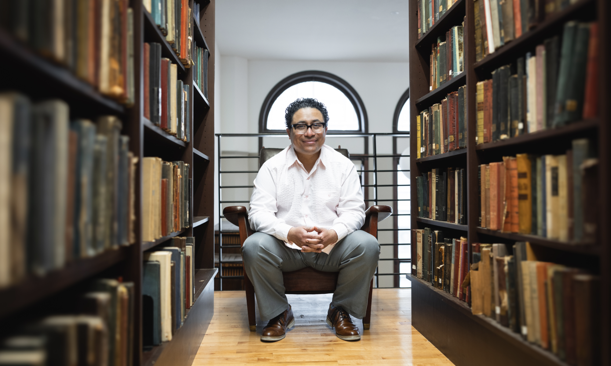 Poet Manuel Iris sitting in a library