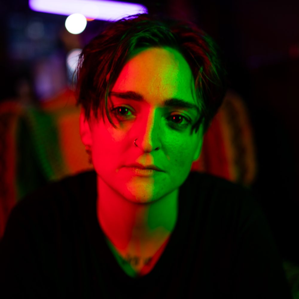 lisa minerva luxx like with red light to the right of their face and green light to the left of their face, looking really cool.